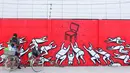 Warga berjualan di depan mural bernuansa politik di Penjaringan, Jakarta, Minggu (7/8). Jelang Pilkada 2017, sejumlah lokasi di Jakarta dihiasi mural politik. (Liputan6.com/Angga Yuniar)