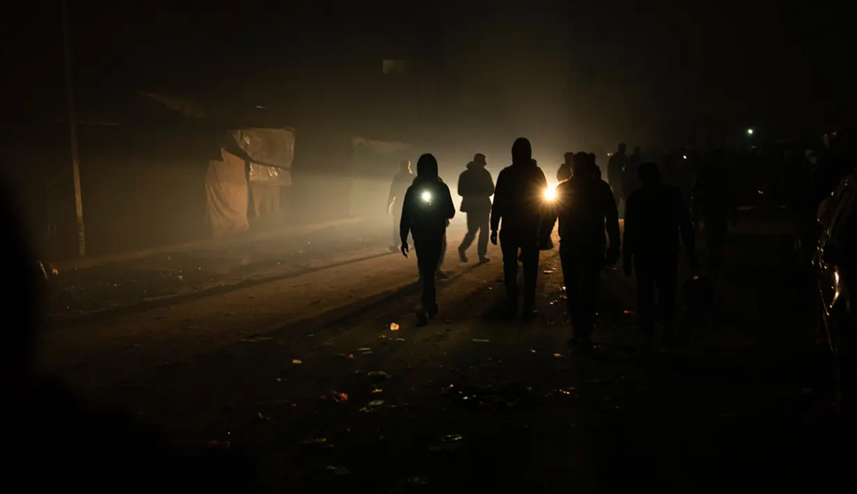 Warga Palestina yang mengungsi akibat pemboman Israel di Jalur Gaza berjalan dalam kegelapan dengan senter di kamp tenda darurat di daerah Muwasi, Minggu (31/12/2023). Israel telah mendorong warga Palestina untuk pindah ke Muwasi, dengan mengatakan bahwa mereka akan aman dari serangan pengeboman Israel. (AP Photo/Fatima Shbair)