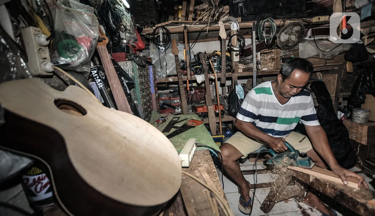 Soedarmadi yang akrab disapa Bone menyelesaikan pembuatan gitar di workshop Bone's Costum Guitar, Jakarta, Rabu (10/3/2021). Untuk mencukupi kebutuhan sehari-hari, ayah dari 4 anak ini mencari sampingan dengan membuka ternak cupang hias sembari menunggu pelanggan gitar. (merdeka.com/Iqbal S Nugroho)