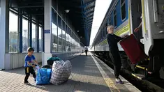 Seorang ibu dan anaknya, salah satu dari ribuan perempuan dan anak-anak yang melarikan diri dari Ukraina setelah Rusia menginvasi, turun dengan barang bawaannya setibanya mereka dari Polandia, di stasiun kereta api Kiev pada 12 Mei 2022. Untuk pertama kalinya sejak awal perang, penghitungan resmi di perbatasan pada 10 Mei menunjukkan 29.000 orang melintasi perbatasan untuk pergi, sedangkan 34.000 orang lainnya melintasi perbatasan untuk kembali ke Ukraina. (Sergei SUPINSKY / AFP)