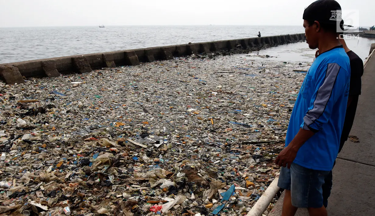 Warga mengamati sampah yang menutupi di pinggir laut kawasan Pelabuhan Muara Baru, Jakarta Utara, Senin (29/7/2019). Sampah-sampah yang didominasi oleh sampah plastik ini terbawa arus laut yang dibuang masyarakat secara sembarangan. (Liputan6.com/Johan Tallo)