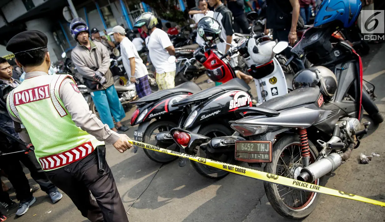 Aparat kepolisian memasang garis polisi di lokasi ledakan bom Kampung Melayu, Kamis (25/5). Lokasi terjadinya ledakan bom dipadati warga untuk berfoto dan melihat langsung peristiwa yang menewaskan tiga polisi tersebut. (Liputan6.com/Faizal Fanani)