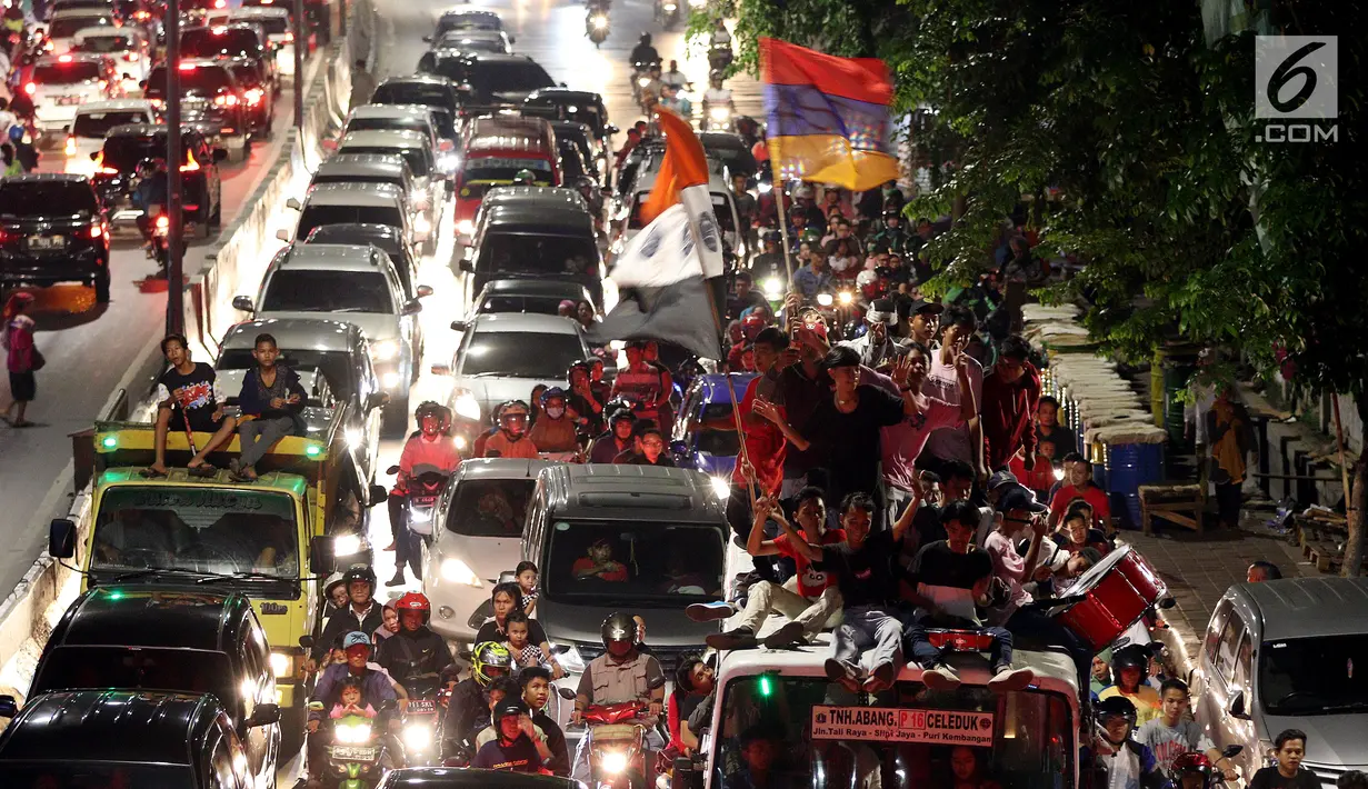 Sejumlah remaja naik berada di atas bus saat melakukan pawai untuk memeriahkan malam takbiran di sepanjang Jalan Mas Mansyur, Tanah Abang, Jakarta Pusat, Kamis (14/6) malam. (Liputan6.com/Johan Tallo)