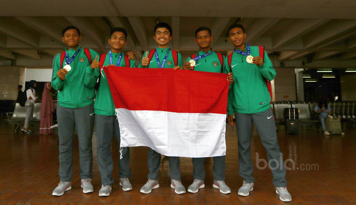 Para pemain Timnas Indonesia U-16 berfoto dengan bendera Merah Putih usai tiba di Bandara Soekarno-Hatta, Cengkareng, Senin (19/6/2017). Timnas U-16 menjadi juara pada ajang Tien Phong Plastic Tournament 2017. (Bola.com/Nicklas Hanoatubun)