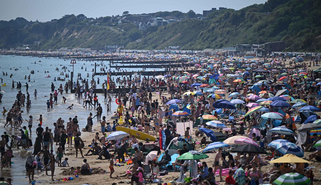 Para pengunjung berjemur menikmati sinar matahari di Pantai Bournemouth, Selatan Inggris pada Selasa 26 Mei 2026, saat kondisi gelombang panas menyebar ke sebagian wilayah tenggara Inggris dan London. (JUSTIN TALLIS/AFP)