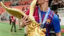 Pemain Barcelona U-18 Xavier Moreno Hernandez mencium trofi juara International Youth Championship (IYC) 2021 di Jakarta International Stadium (JIS), Jakarta, Selasa (19/4/2022). Barcelona U-18 juara IYC 2021 usai menang atas Altetico Madrid U-18. (Liputan6.com/Faizal Fanani)