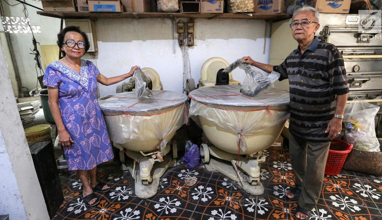 Rosani, generasi ketiga (kiri) dan suaminya Pararto Widjajakusuma (kanan) berfoto bersama di antara adonan kue peninggalan Belanda di Toko Roti GO, Purwokerto, Jawa Tengah, Senin (22/4). Toko roti yang berdiri sejak tahun 1898 itu telah memasuki usia ke 121 tahun. (Liputan6.com/Fery Pradolo)