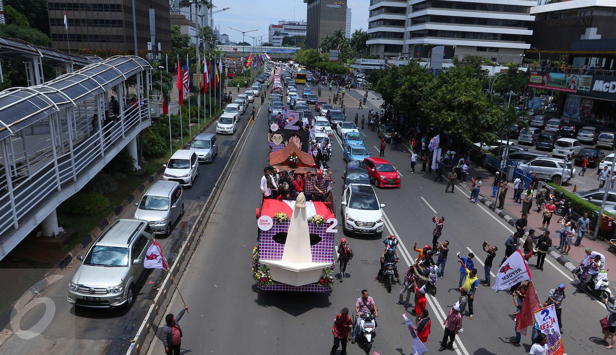 Sejumlah warga melihat Iring-iringan mobil karnaval para pasangan Cagub DKI Jakarta saat melintas di Thamrin, Jakarta, Sabtu (29/10). Karnaval tersebut merupakan bentuk kampanye damai untuk pemilihan Gubernur DKI Jakarta. (Liputan6.com/Angga Yuniar)