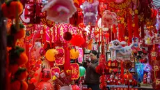 Seorang pembeli memotret dekorasi Tahun Baru Imlek di sebuah pasar di Beijing, China, Rabu 4 Februari 2026. Imlek merupakan sebuah perayaan yang sangat penting bagi masyarakat China. Perayaan tahun baru ini didasarkan oleh penanggalan lunar (bulan). (AP Photo/Vincent Thian)