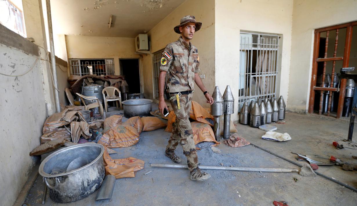 Seorang pasukan anggota pasukan kontraterorisme Irak melintas di bangunan yang digunakan sebagai pabrik senjata militan ISIS yang berhasil ditemukan di Fallujah, Irak, Kamis (23/6). (REUTERS/Thaier Al-Sudani)