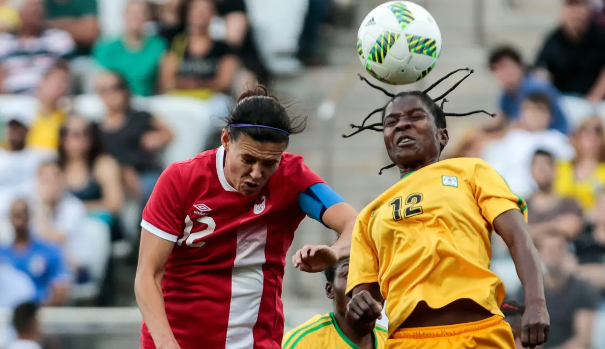 Marjory Nyaumwe berebut bola udara dengan pemain Kanada, Christine Sinclair di Grup F Olimpiade Rio 2016 di Korintus Arena, Brasil, (6/8). Atlet 29 tahun ini mengepang rambut gimbalnya ke atas yang jadi sorotan. (AFP PHOTO/Miguel SCHINCARIOL)
