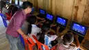 Seorang guru memberikan pelajaran penggunaan komputer kepada siswa Coconut School di  Taman Nasional Kirirom Kamboja, 1 Oktober 2018. Ada sekitar 65 anak yang terdaftar menjadi murid di sekolah yang dibuka sejak 1,5 tahun lalu itu. (TANG CHHIN Sothy/AFP)