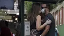Pasangan yang mengenakan masker dan sarung tangan berciuman saat mengantre untuk membeli tiket kereta di Rio de Janeiro, Brasil, 17 Maret 2020. Organisasi Kesehatan Dunia (WHO) mengumumkan virus corona COVID-19 sebagai pandemi sejak 11 Maret 2020 lalu. (MAURO PIMENTEL/AFP)