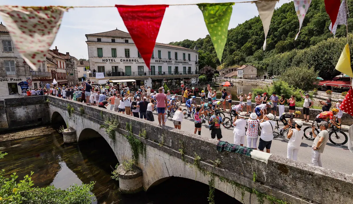 Pembalap melewati jembatan saat beraksi pada ajang Tour de France 2023 di Limoges, Prancis (8/7/2023). Balapan ini total memakan waktu selama tiga minggu atau sekitar 23 Etape. (Photo by Thomas SAMSON / AFP)
