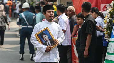 Kerabat membawa foto almarhum Wakil Presiden ke-9 Republik Indonesia, Hamzah Haz di Jalan Tegalan, Matraman, Jakarta, Rabu (24/7/2024). (Liputan6.com/Angga Yuniar)