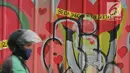 Pengendara melintasi mural yang menghiasi tembok di kawasan Margonda, Depok, Sabtu (16/2). Gambar mural memiliki pesan agar masyarakat tetap damai dan berteman meski berbeda dalam memilih calon presiden dalam Pilpres 2019. (Liputan6.com/Herman Zakharia)