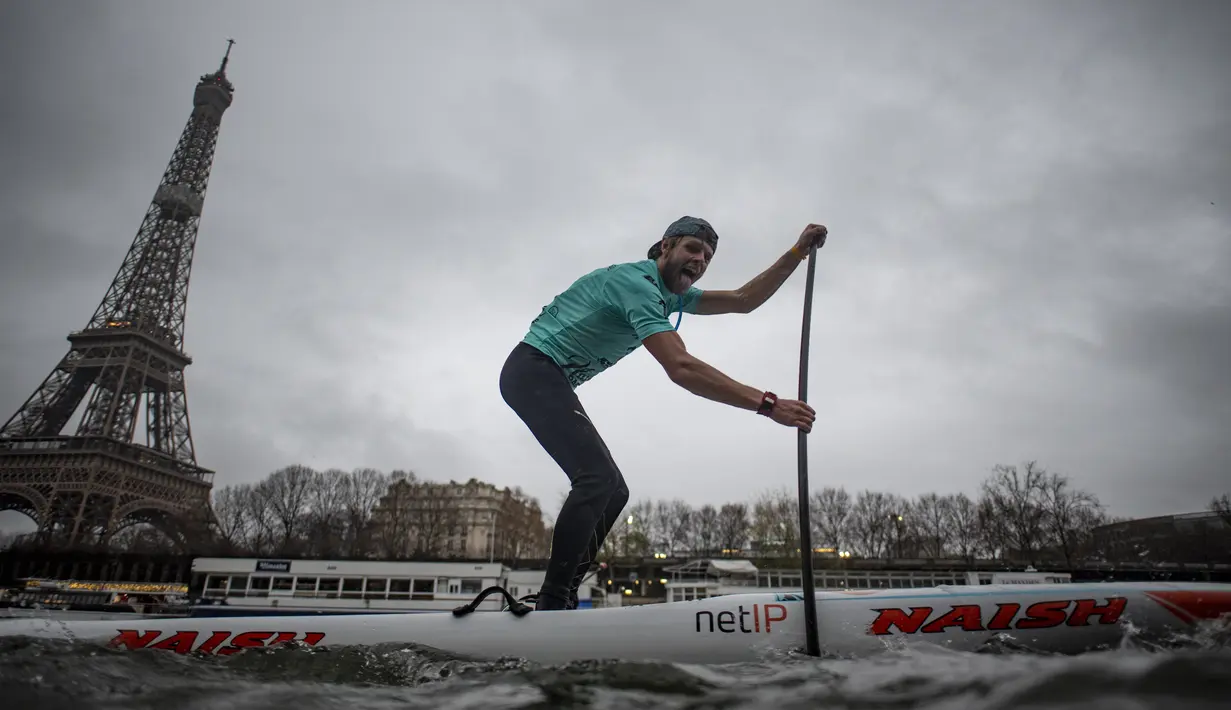 Peserta Nautic Paddle Race atau lomba dayung sambil berdiri melintas dekat Menara Eiffel di Sungai Seine, Paris, Minggu (8/12/2019). Sekitar 1000 pesaing ikut serta dalam lomba sejauh 11 kilometer menyeberangi sungai Seine dengan pemandangan kota Paris. (Photo by Olivier MORIN / AFP)