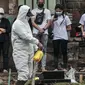 Petugas menyemprotkan disinfektan di area makam pasien Covid-19 di TPU Pondok Kelapa, Jakarta, Selasa (13/7/2021). Tim Koalisi Warga LaporCovid-19 mencatat sebanyak 451 pasien Covid-19 meninggal saat menjalani isolasi mandiri. (merdeka.com/Iqbal S Nugroho)