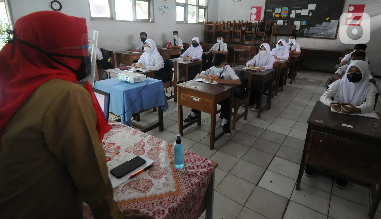Guru mengajar para murid saat pelaksanaan uji coba pendidikan tatap muka (PTM) di SMPN 15, Kota Bogor, Jawa Barat, Senin (31/5/2021). Pemerintah Kota Bogor menggelar uji coba PTM di 37 sekolah hari ini dengan protokol kesehatan yang ketat. (merdeka.com/Arie Basuki)