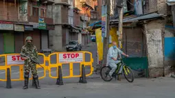 Pria Kashmir melintasi barikade yang digunakan untuk memblokir jalan di Srinagar, Kashmir yang dikuasai India, Rabu (5/8/2020). Tentara India memperketat keamanan di Kashmir dalam upaya menahan serangan dalam peringatan setahun pelepasan status otonomi khusus wilayah tersebut. (AP Photo/ Dar Yasin)