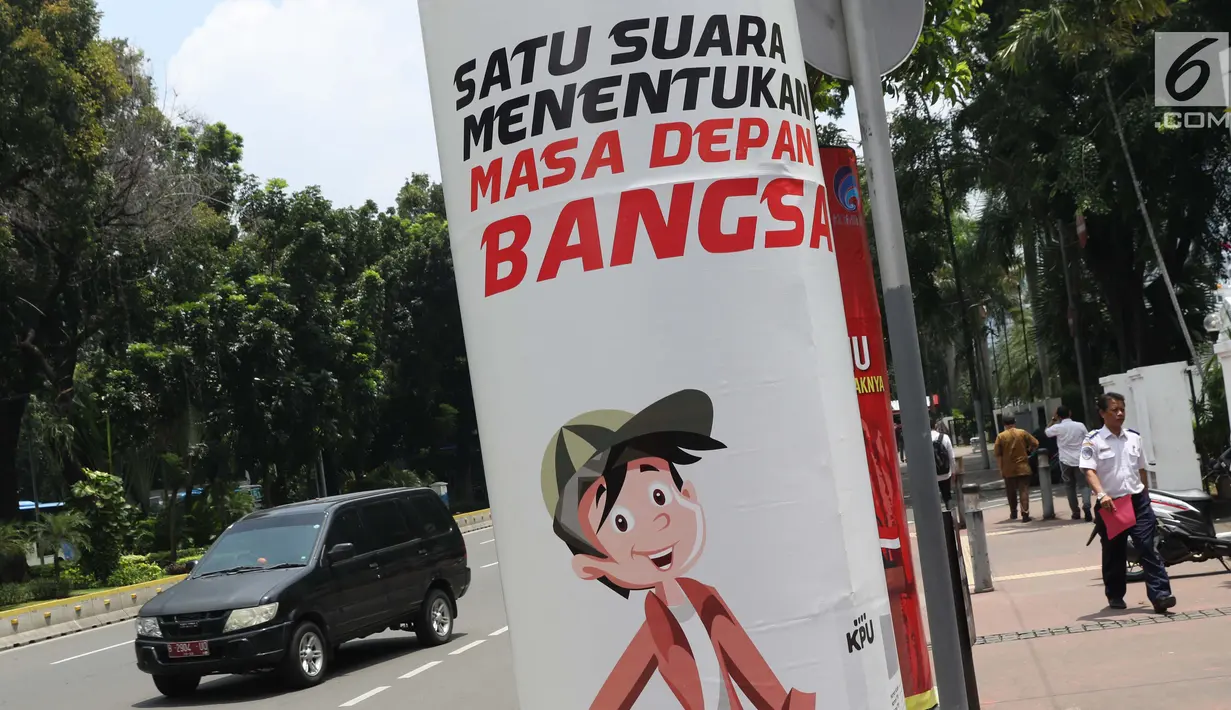 Pejalan kaki melintas di sisi media sosialisasi pelaksanaan Pemilu Serentak 2019 di depan kantor Kemenkominfo jalan Medan Merdeka Barat, Jakarta, Selasa (26/2). KPU menargetkan tingkat pemilih mencapai 77,5 persen. (Liputan6.com/Helmi Fithriansyah)