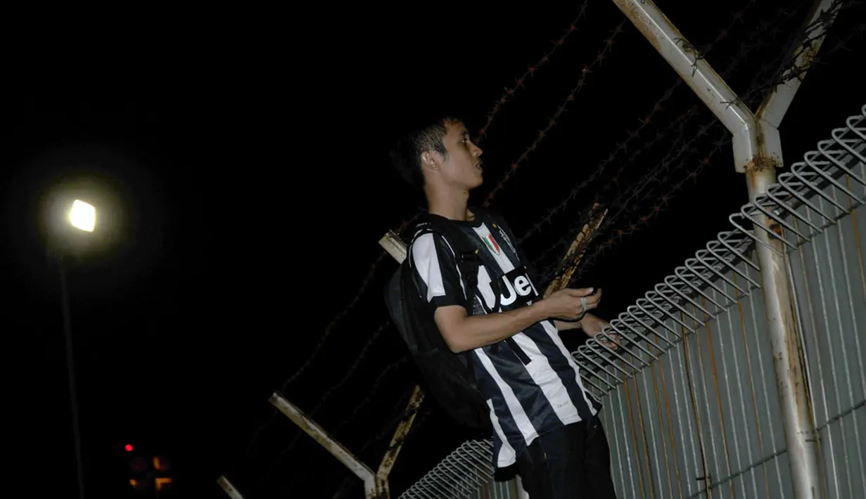 Salah satu suporter Juventus nekat memanjat pagar Bandara Soekarno-Hatta, untuk mengabadikan kedatangan La Vecchia Signora, (4/8/2014). (Liputan6.com/Helmi Fithriansyah)