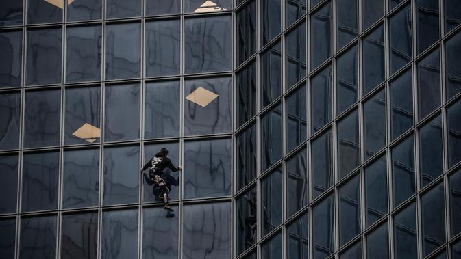 Pendaki Alain Robert atau French Spiderman memanjat Menara Total di kawasan bisnis La Defense, Paris, Prancis, Senin (13/1/2020). Alain memanjat gedung 48 lantai tersebut sebagai dukungan untuk pekerja yang mogok karena menentang reformasi pensiun di Prancis. (Thomas SAMSON/AFP)