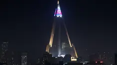 Pertunjukan cahaya menampilkan bendera Korea Utara di atas hotel Ryugyong di kota Pyongyang, Korea Utara (9/4). (AFP Photo/Ed Jones)