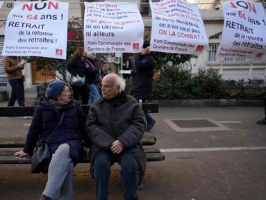 Sepasang lansia duduk di bangku saat para pengunjuk rasa berbaris dalam demonstrasi menentang rencana untuk menunda usia pensiun Prancis, Paris, Selasa (31/1/2023). Pemogokan dan protes nasional ini merupakan ujian penting bagi pemerintahan Presiden Emmanuel Macron dan para penentangnya. (AP Photo/Christophe Ena)