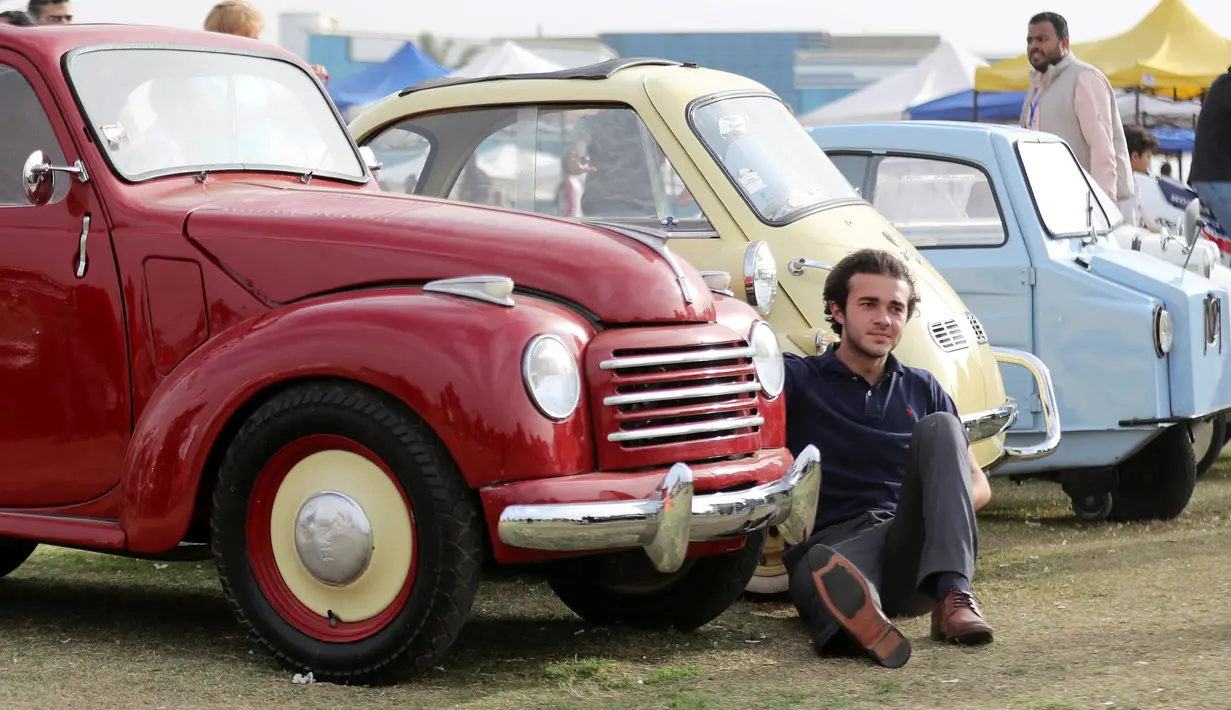 Seorang pria berpose di samping Fiat 500C Topolino klasik merah saat pertemuan klasik Kairo ke-7 di Kairo, Mesir (23/3). (Reuters/Mohamed Abd El Ghany)