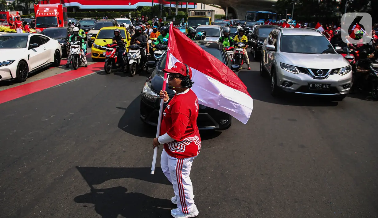 Warga dan pengguna jalan yang melintasi kawasan Bundaran HI antusias mengikuti upacara pengibaran Bendera Merah Putih secara virtual. (Liputan6.com/Angga Yuniar)