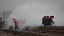 Orang-orang menikmati percikan air ombak selama musim panas di laut Arab di Karachi, Pakistan (14/6/2019). Memasuki musim panas, warga Pakistan ramai-ramai mendinginkan tubuhnya di laut. (AFP Photo/Asif Hassan)