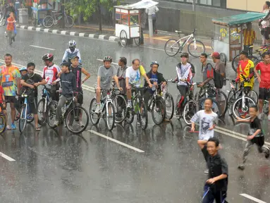 Hujan mengguyur kawasan Bundaran HI saat kegiatan Car Free Day di Jakarta, Minggu (24/1/2016). Sejumlah pengunjung tetap melaksanakan olahraga di bawah guyuran hujan. (Liputan6.com/Helmi Affandi)
