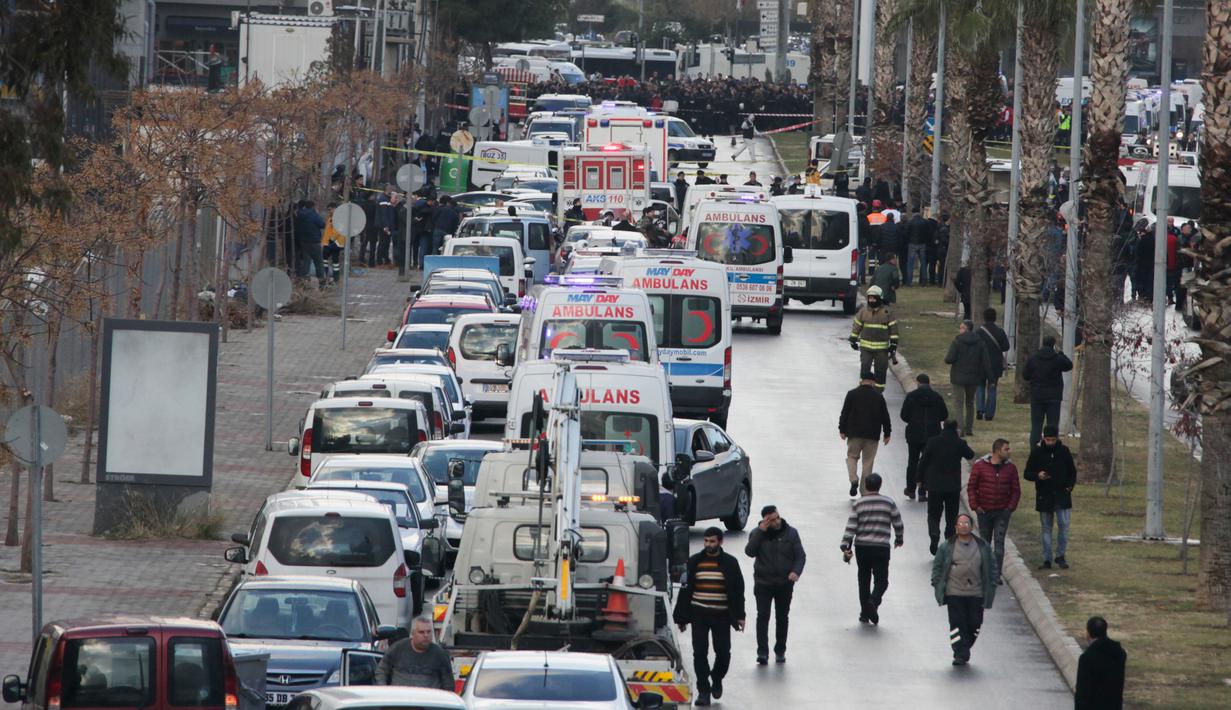 Sejumlah orang berjalan melewati ambulan yang dikerahkan ke lokasi ledakan di luar sebuah pengadilan di kota Izmir, wilayah barat Turki, Kamis (5/1). Paramedis langsung diterjunkan ke lokasi dan merawat para korban yang terluka. (AFP PHOTO/Emre TAZEGUL)