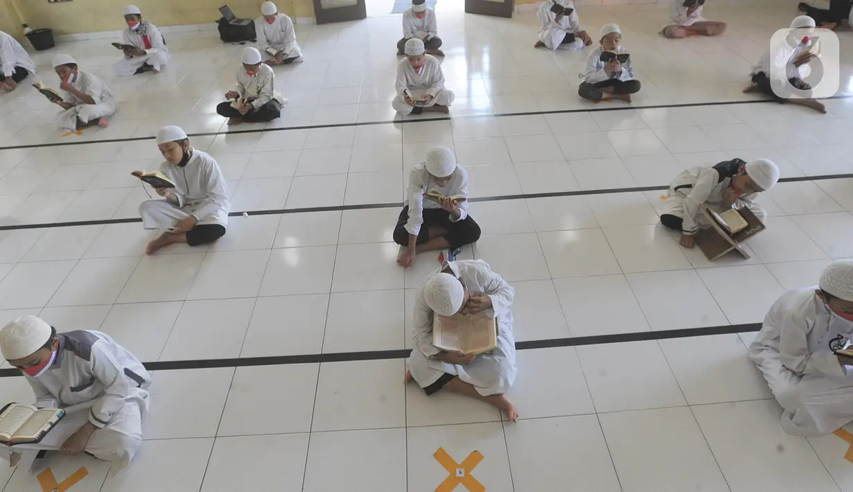 Sejumlah santri berusia belasan tahun membaca Al quran atau tadarus bersama-sama dengan menerapkan jaga jarak di Masjid Daarul Qu'ran Pesantren Al Kautsar, Cibinong, Bogor, Kamis (7/5/2020). Kegiatan Khatam Al quran tersebut dilakukan rutin di setiap bulan Ramadan. (merdeka.com/Arie Basuki)