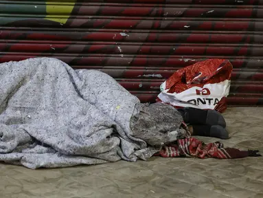 Seorang tunawisma tidur di atas trotoar saat malam dengan cuaca dingin di pusat kota Sao Paulo, 19 Juli 2017. Menurut pejabat setempat, setidaknya 16.000 tunawisma tinggal di kota Sao Paulo. (AP Photo / Andre Penner)