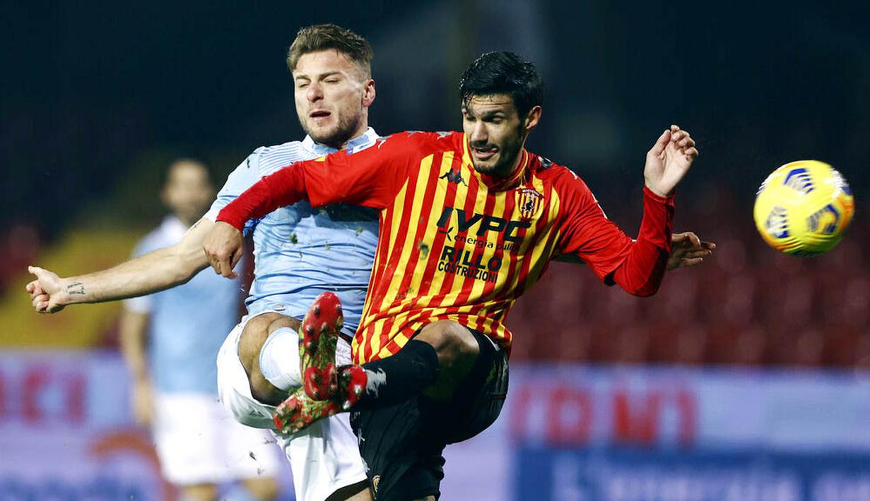 Striker Lazio, Ciro Immobile, berebut bola dengan pemain Benevento pada laga Liga Italia di Stadion Vigorito, Rabu (16/12/2020). Kedua tim bermain imbang 1-1. (Alessandro Garofalo/LaPresse via AP)