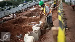 Pekerja memadatkan celah  saat pembangunan jalur LRT seksi Cawang-Cibubur, Jakarta, Kamis (8/12). Jalur LRT ini nantinya akan digunakan sebagai salah satu transportasi dalam pelaksanaan Asian Games 2018 .(Liputan6.com/Faizal Fanani)