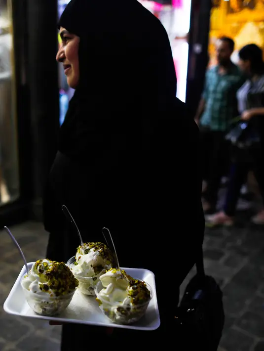 Seorang wanita Suriah membeli es krim di pasar Hamadiyah, atau souk dalam bahasa Arab, yang diberi nama setelah Sultan ke-34 Kekaisaran Ottoman Abdul Hamid II, di Kota Tua Damaskus, Suriah, (14/7). (AP Photo / Hassan Ammar)
