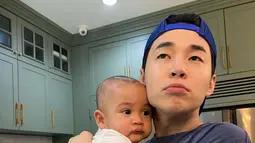 Rayyanza Malik Ahmad tampak anteng digendong oleh Henry Lau. Gemasnya, keduanya memperlihatkan ekspresi wajah yang sama. (Foto: Instagram/ henryl89)