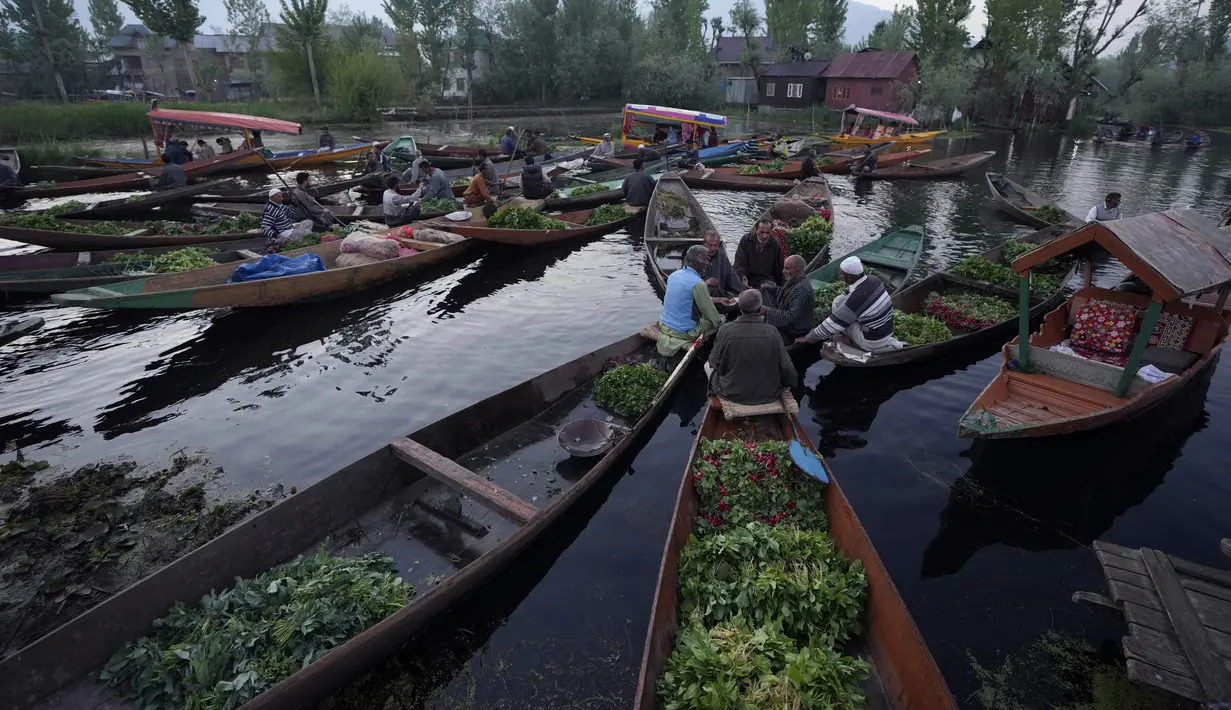 Laki-laki Kashmir menjual produk mereka di pasar sayuran terapung di Danau Dal, Srinagar, Kashmir yang dikuasai India, Kamis (7/4/2022). (AP Photo/Rajesh Kumar Singh)
