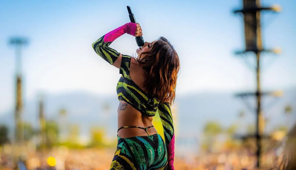 Anitta mengguncang panggung Coachella 2022 dengan outfit yang colorful. Crop top dengan desain off-shoulder lengan panjang, serasi dengan legging panjang bermotif loreng macan berwarna-warni. Foto: Instagram.