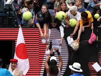 Petenis Jepang Naomi Osaka menandatangani benda yang disodorkan penonton usai mengalahkan petenis Republik Ceko Marie Bouzkova pada Australia Terbuka di Melbourne, Australia, Senin (20/1/2020). Penonton menyodorkan topi, bendera, hingga bola untuk ditandatangani Naomi. (AP Photo/Lee Jin-man)