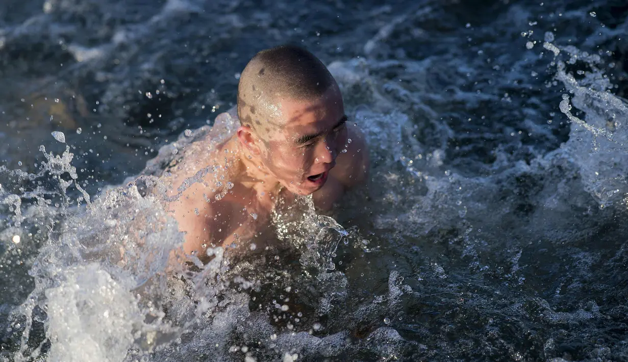 Seorang pria berenang di danau Hou Hai yang membbeku di Beijing, China (24/1). (AFP Photo/Nicolas Asfouri)