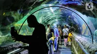 Wisatawan melihat ikan di tempat wisata kawasan Ancol, Jakarta, Minggu (8/1/2023). Saat ini kinerja sektor pariwisata dan ekonomi kreatif pada 2023 dihadapkan dengan target yang cukup tinggi. Kunjungan wisman diharapkan mencapai angka 7,4 juta dan wisatawan nusantara mencapai 1,2-1,4 miliar pergerakan. (Liputan6.com/Angga Yuniar)