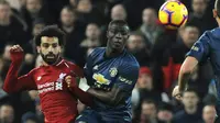 Striker Liverpool, Mohamed Salah berebut bola dengan pemain Manchester United, Eric Bailly dalam lanjutan pekan ke-17 Premier League di Stadion Anfield, Minggu (16/12). The Reds mengalahkan rival abadi, Manchester United dengan skor 3-1. (AP/Rui Vieira)