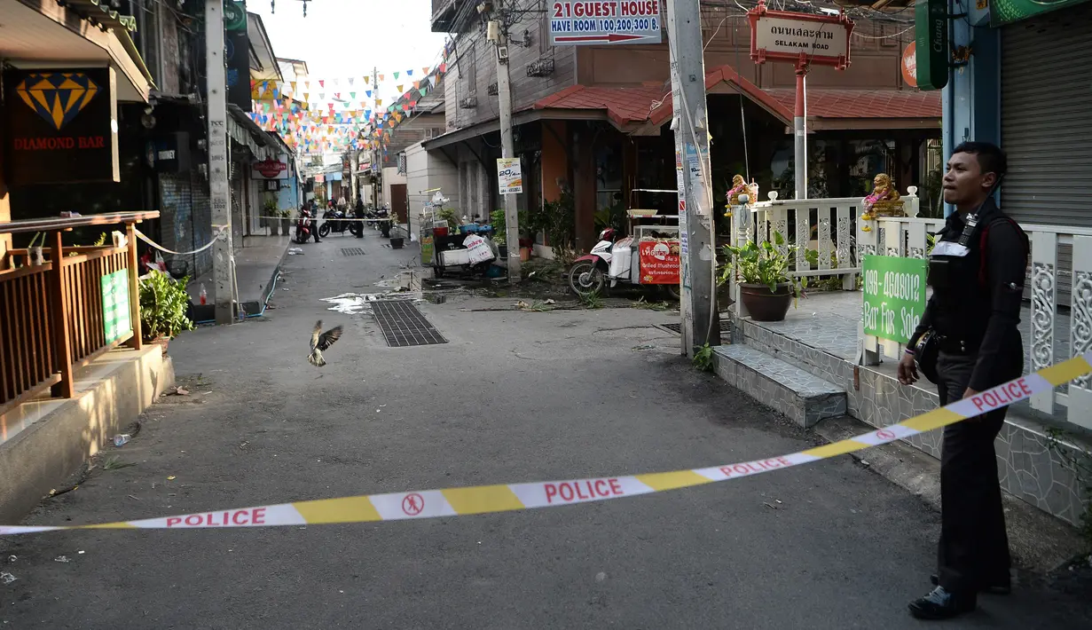 Seorang polisi berjaga di lokasi ledakan bom kembar di kawasan resor  Hua Hin, Thailand, Jumat (12/8). Ledakan yang terjadi di wilayah cukup terkenal di kalangan turis itu menewaskan satu orang dan melukai 19 lainnya. (Munir Uz ZAMAN/APF/AFP)