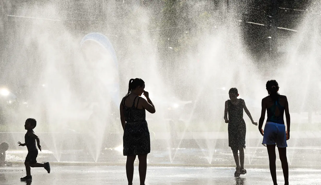 Sejumlah warga menyejukkan diri di dekat semprotan air di Schwarzenbergplatz di Wina, Austria (28/7/2020). Suhu tertinggi di Wina mencapai angka 37,2 derajat Celsius pada Selasa (28/7). (Xinhua/Guo Chen)