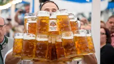 Oliver Struempfel membawa gelas bir sebanyak-banyaknya sambil berjalan untuk memecahkan rekor saat bersaing pada festival tradisional Gillamoos di Abensberg, Jerman, Minggu (3/9). Struempfel berhasil menyusun 29 gelas bir besar. (Matthias Balk/dpa via AP)