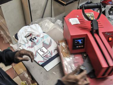 Pekerja menyelesaikan sablon jersey sepak bola di salah satu kios Blok B Pasar Tanah Abang, Jakarta Pusat, Kamis (8/12/2022). Perhelatan Piala Dunia 2022 membawa berkah tersendiri bagi jasa sablon jersey sepak bola di Pasar Tanah Abang yang diakui mengalami peningkatan pesanan hingga 80 persen dibandingkan bulan sebelumnya. (merdeka.com/Iqbal S. Nugroho)
